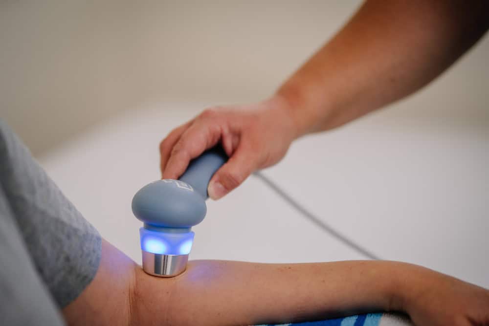 A close-up of a therapist using a handheld therapeutic device on